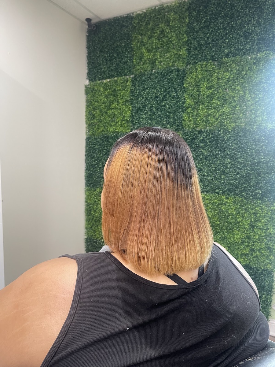 Caramel bob styled against the salon's greenery wall